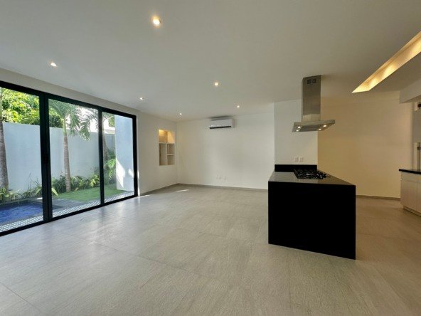 Casa en venta av huayacan - Amplia sala de estar con grandes ventanales corredizos de cristal que dan hacia una alberca