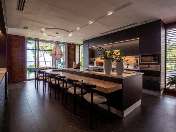 Casa venta isla dorada zona hotelera cancún - barra de la cocina, al fondo la cocina integral con detalles oscuros