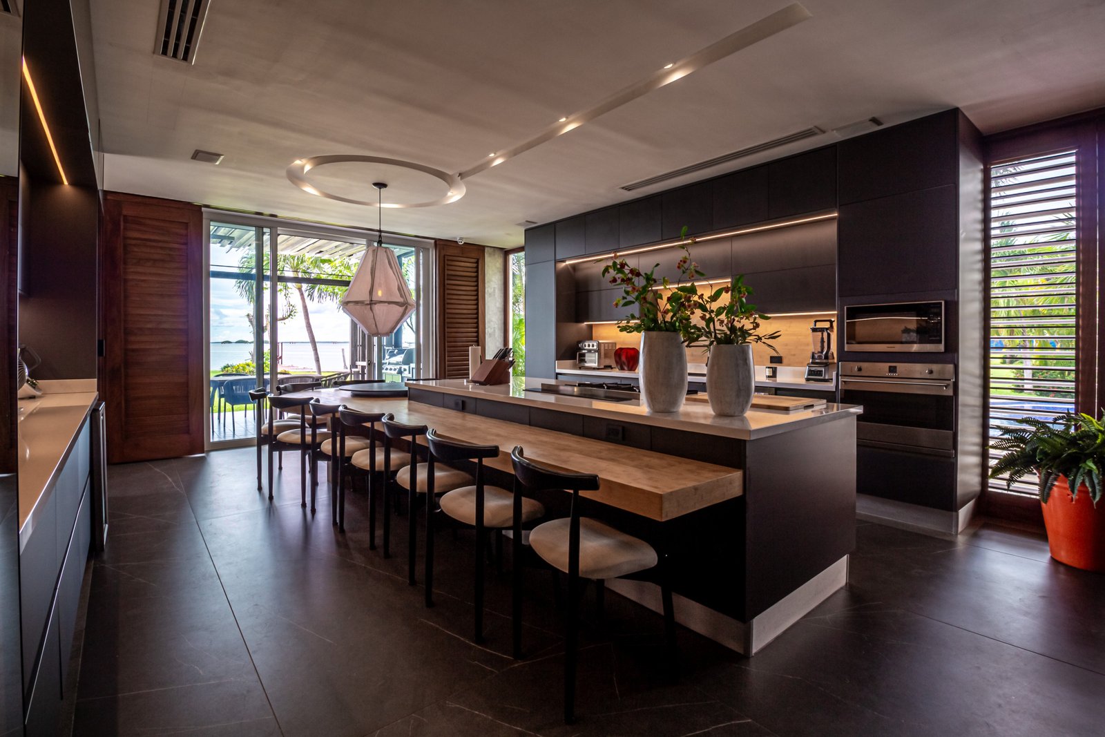 Casa venta isla dorada zona hotelera cancún - barra de la cocina, al fondo la cocina integral con detalles oscuros