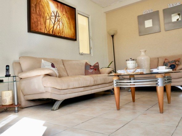 Departamento en venta en centro cancún - Sala de estar con sofás de tonos neutros y mesa de centro de cistal