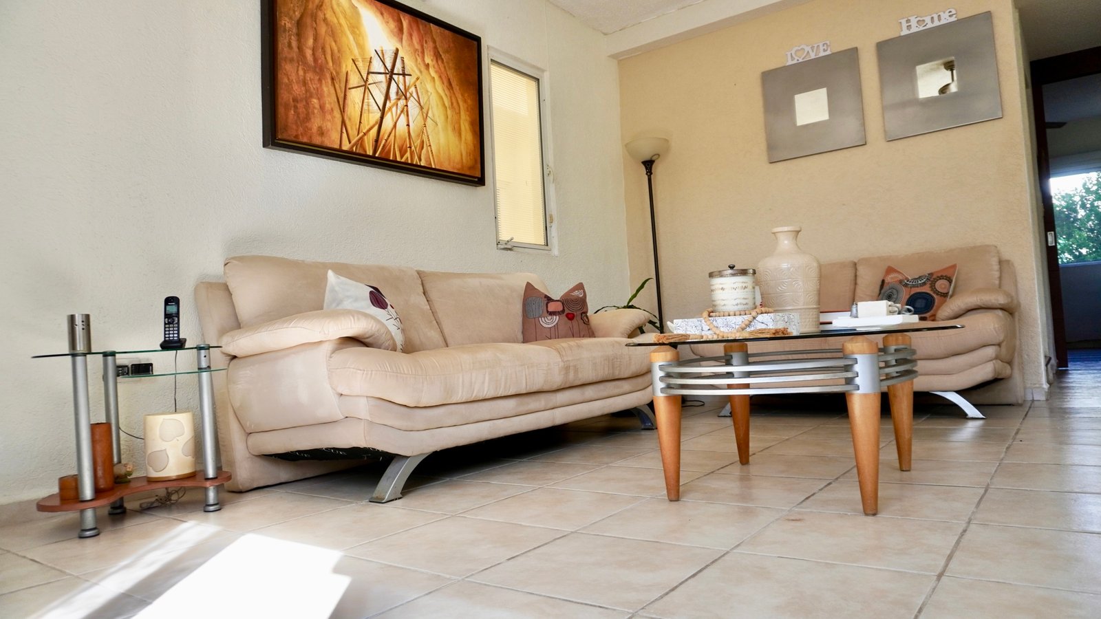 Departamento en venta en centro cancún - Sala de estar con sofás de tonos neutros y mesa de centro de cistal